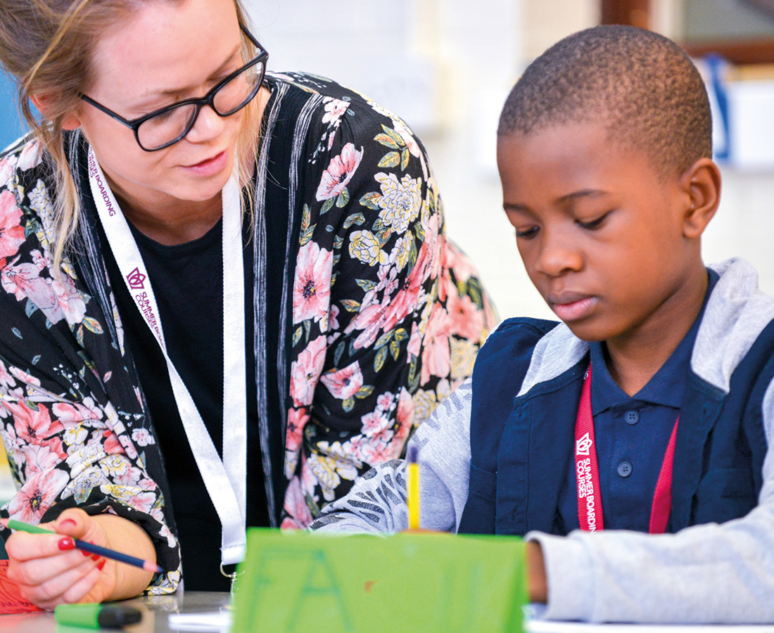 Female teacher with male student supporting him with his work in class