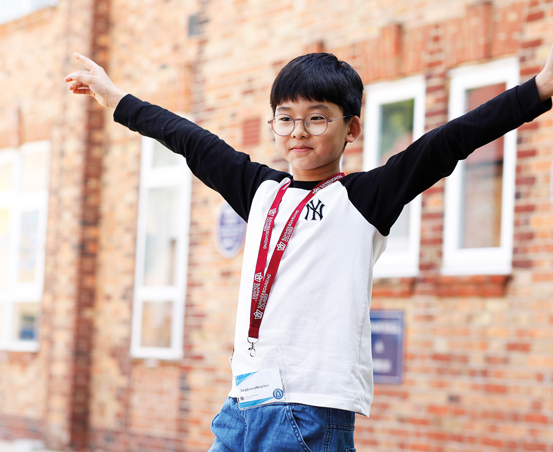 Male student at camp dragon with arms stretched high and smiling